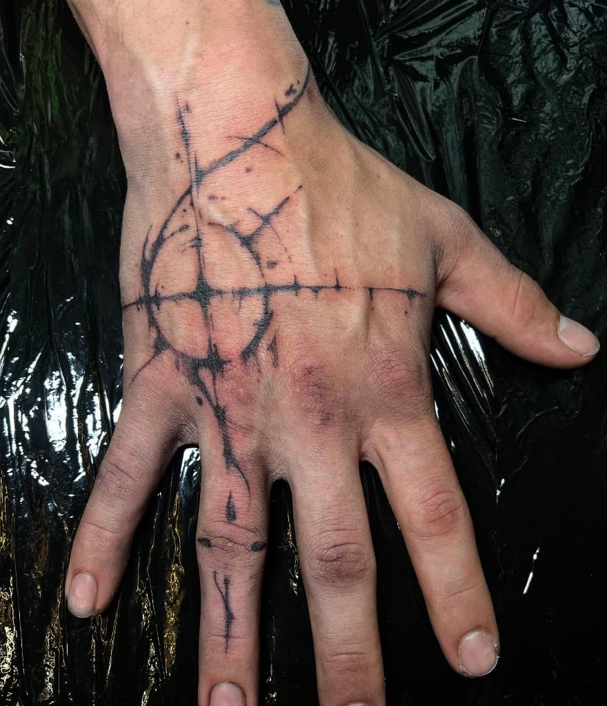 Fresh geometric tattoo on the back of a hand: intersecting lines, a circle, and a line down the middle finger.